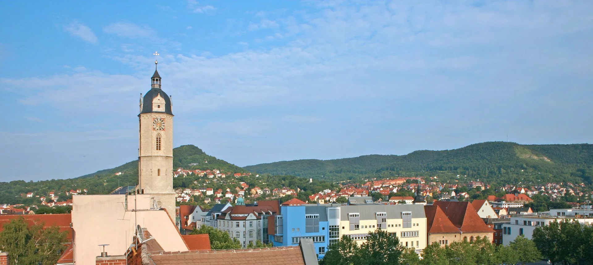 Eine Stadtansicht von Jena mit einem Glockenturm im Hintergrund.
