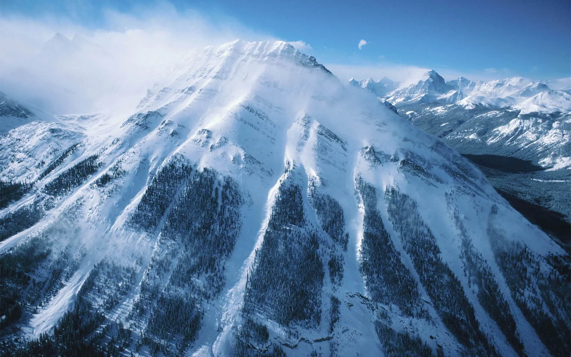 Eine Luftaufnahme eines schneebedeckten Berges, der seine majestätische Schönheit zeigt.