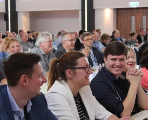 Eine Gruppe von AKOS sitzt auf einer Konferenz.