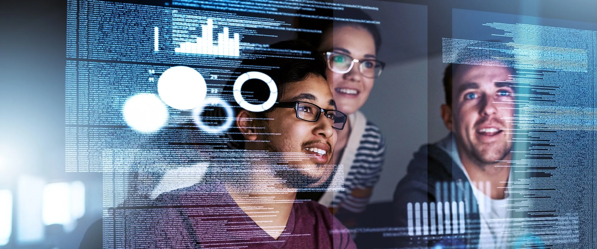 Zwei Männer und eine Frau schauen auf Computercode, der vor ihnen zu schweben scheint