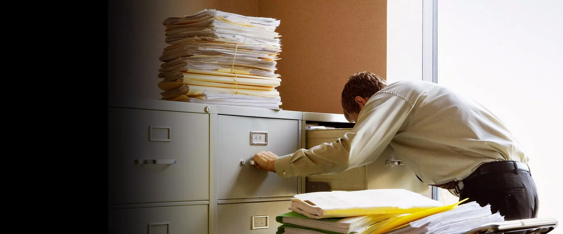 Ein Mann organisiert Papiere in einem Dokumentenarchiv (Aktenschrank).