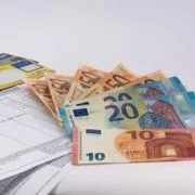 Euro-Banknoten und Dokumente auf einem weißen Tisch.