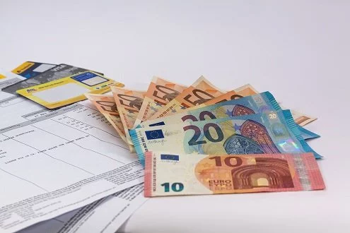 Euro-Banknoten und Dokumente auf weißem Hintergrund.