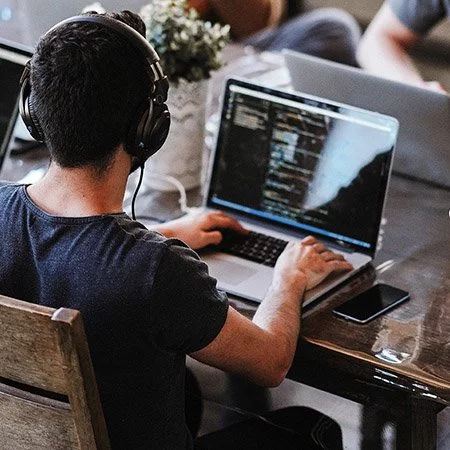 Eine Gruppe von Menschen, die an einem Tisch an Laptops arbeiten.