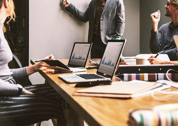 Eine Gruppe von Menschen sitzt mit Laptops an einem Tisch und arbeitet am Dokumentenmanagement.