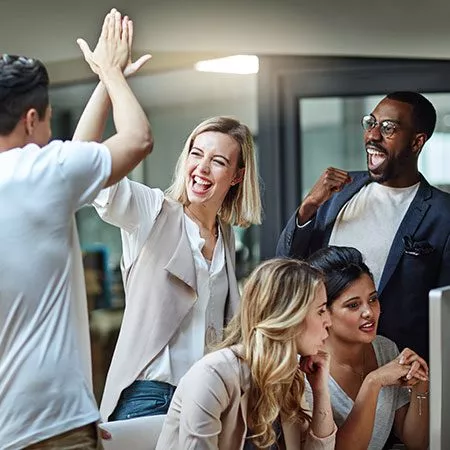 Eine Gruppe von Leuten, die sich in einem Büro gegenseitig High-Five geben.