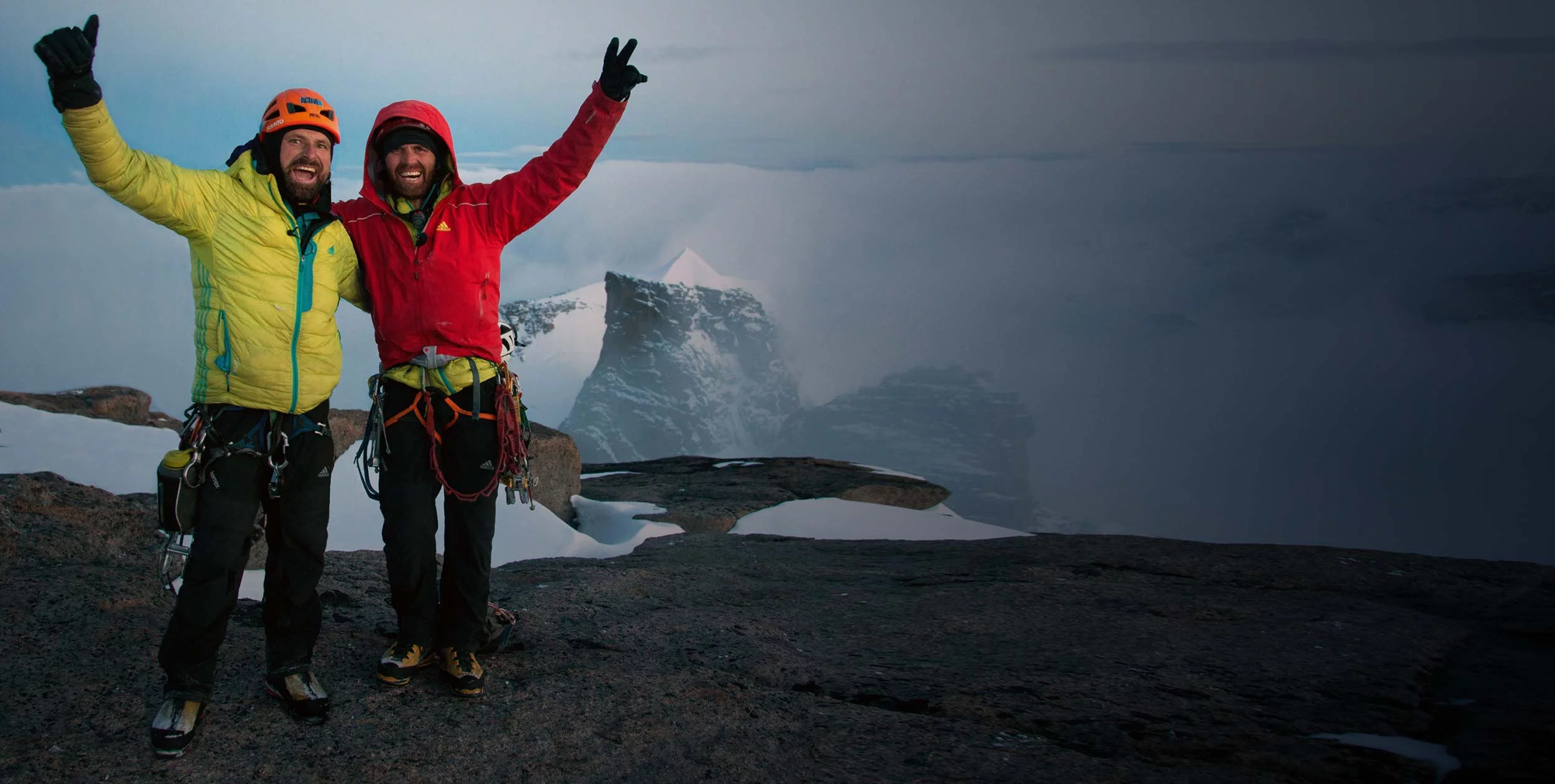 Huberbuam stehen mit erhobenen Armen auf einem Berggipfel