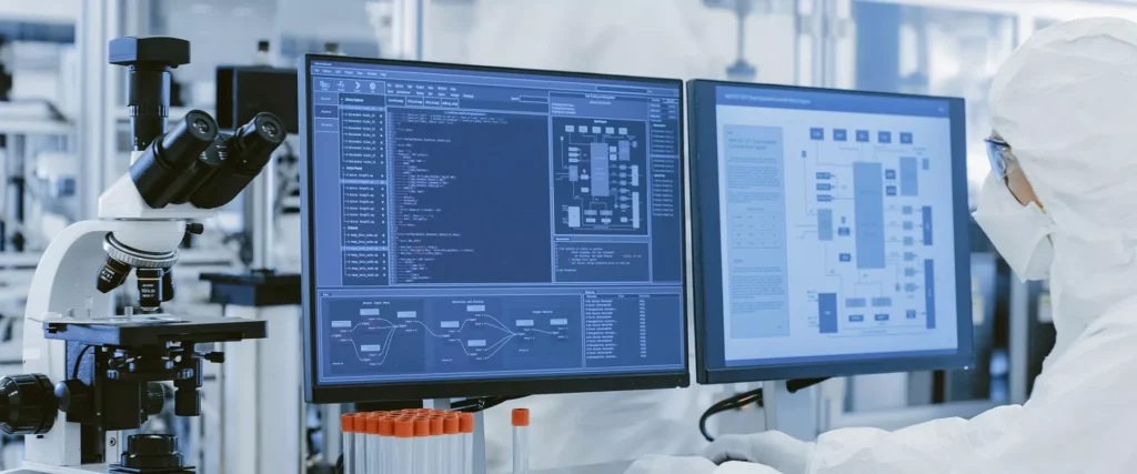 Ein Mann im weißen Laborkittel bedient ein LIMS-System und blickt dabei auf zwei Monitore.