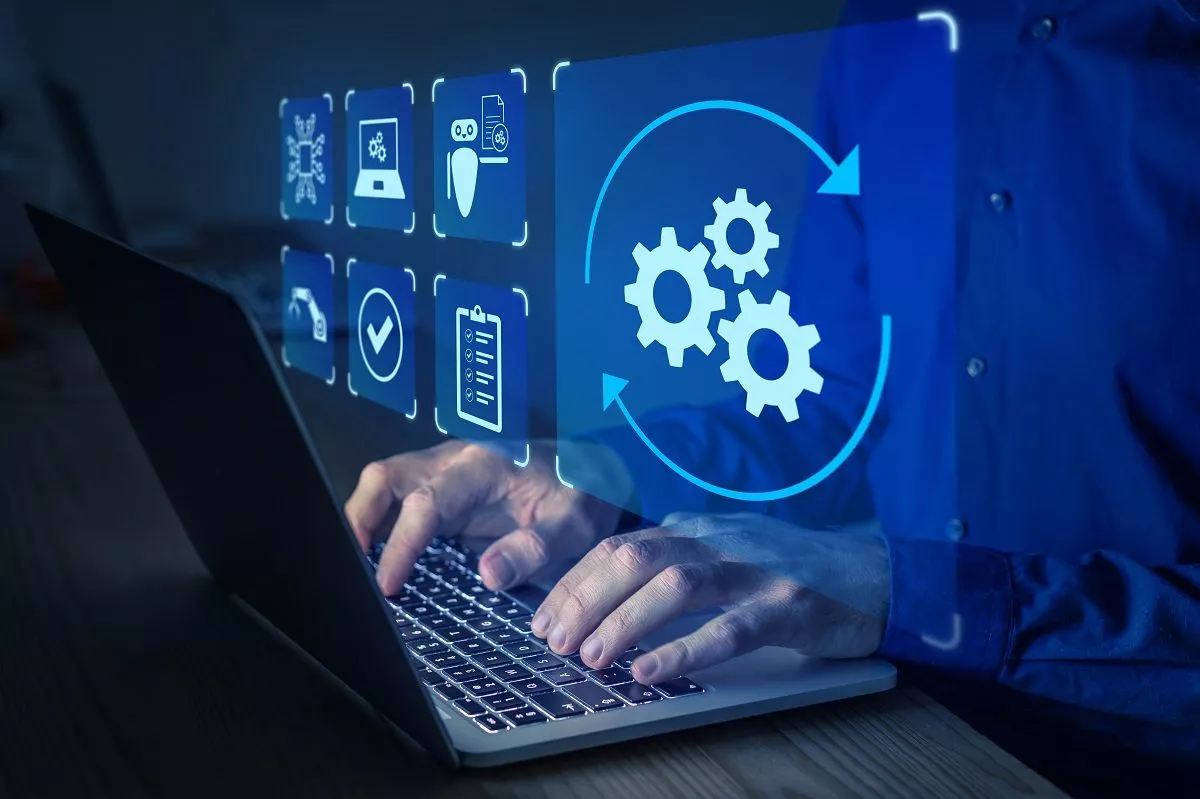 Tippende Männerhände auf einem Laptop mit diversen Prozess-Icons als Overlay