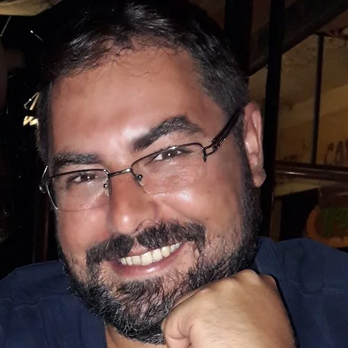 A man with glasses and a beard smiling for the camera while representing his team in Belgrade.