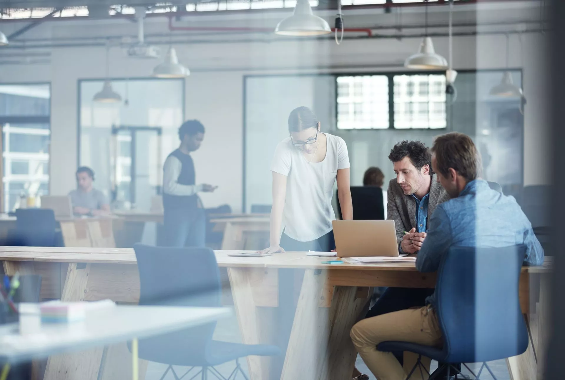 Eine Gruppe von Personen, die in einem Büro arbeiten und auf ein Laptop auf einem Tisch schauen