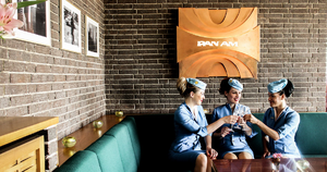 Eine Gruppe Flugbegleiterinnen in blauen Vintage-Uniformen sitzt an einem Tisch. in der Berliner Pan Am Lounge