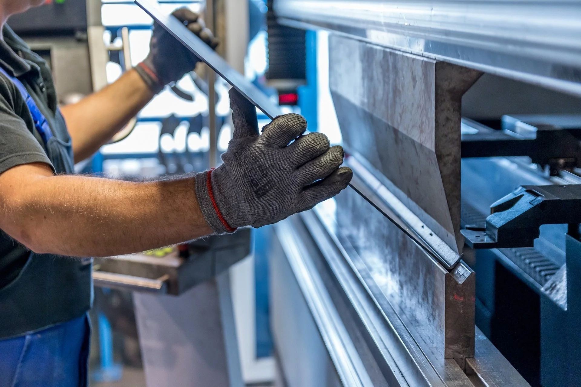 Ein Mann arbeitet an einer Maschine in einer Fabrik und beschäftigt sich dabei mit dem Aspekt der Digitalisierung im Kontext kleiner und mittlerer Unternehmen.