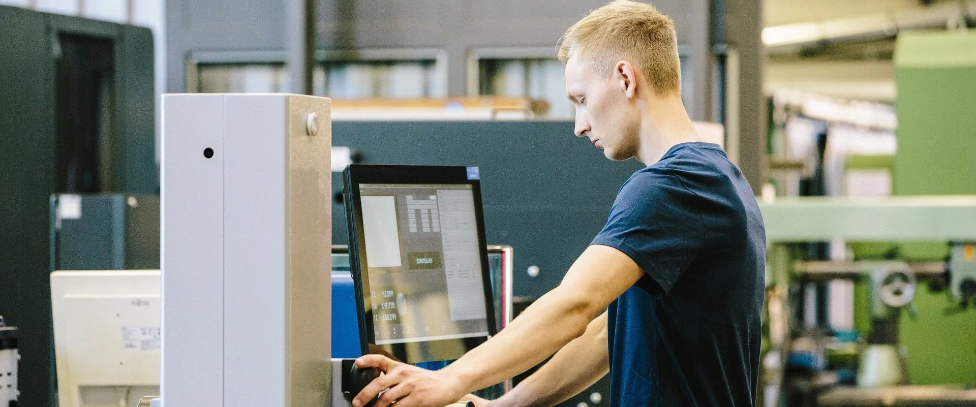 Ein Mann, der eine Ausbildung absolviert, während er in einer Fabrik eine Maschine bedient.