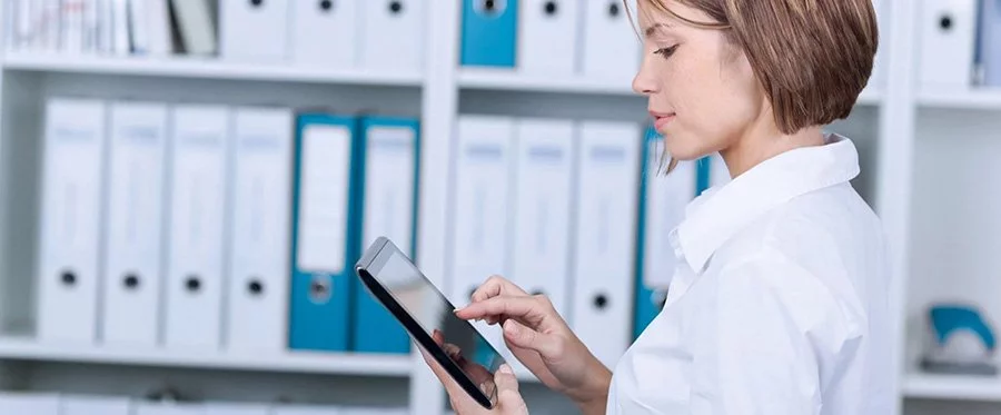 Eine Frau nutzt ein Tablet in einem Büro mit Insellösungen.