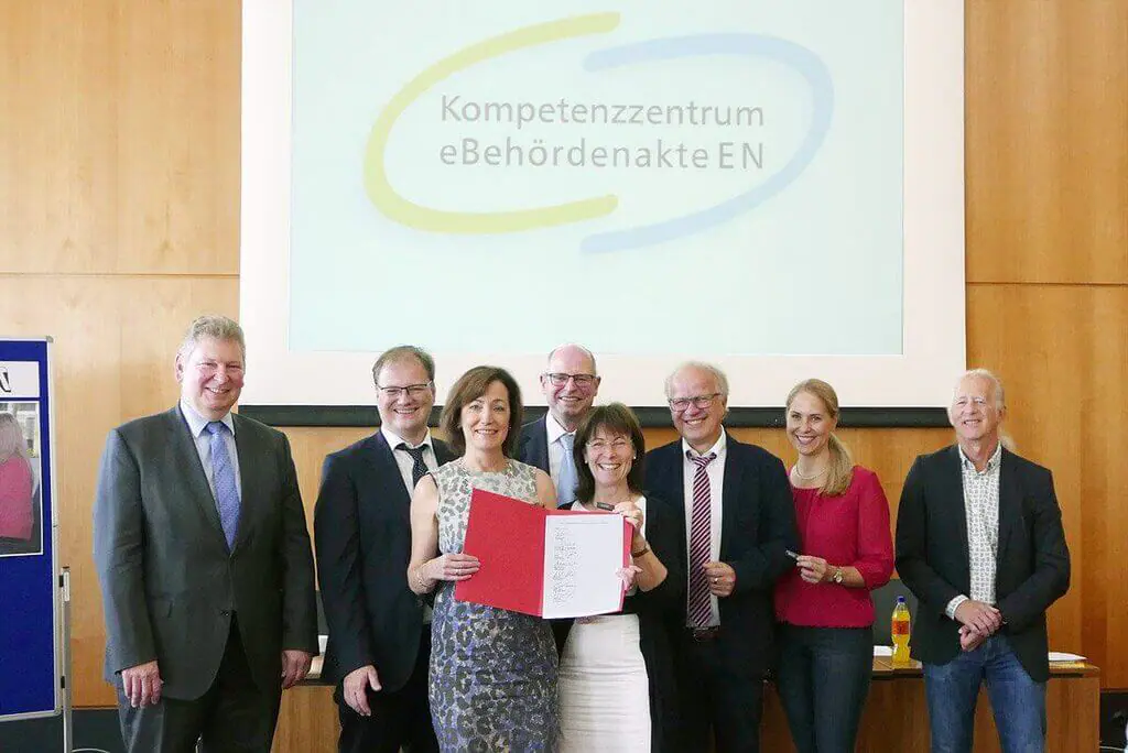 Eine Gruppe von eAkte-Nutzern posiert vor einem Bildschirm für ein Foto.