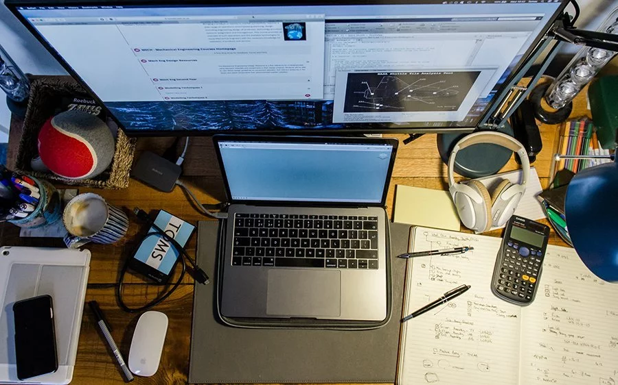 Ein Home-Office-Schreibtisch mit einem Laptop, einem Telefon und anderen Gegenständen darauf.