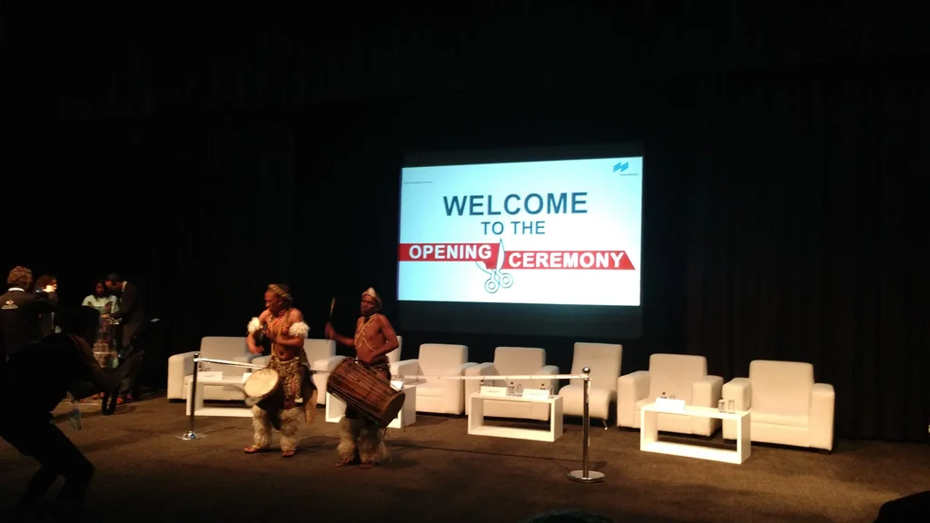 Screen displaying &#039;Welcome to the Opening Ceremony&#039; with a ribbon-cutting graphic.