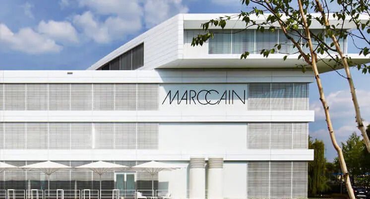 Textilbranche: Das Bild zeigt ein modernes weißes Gebäude mit dem markanten Schriftzug „Marc Cain“ an der Fassade.